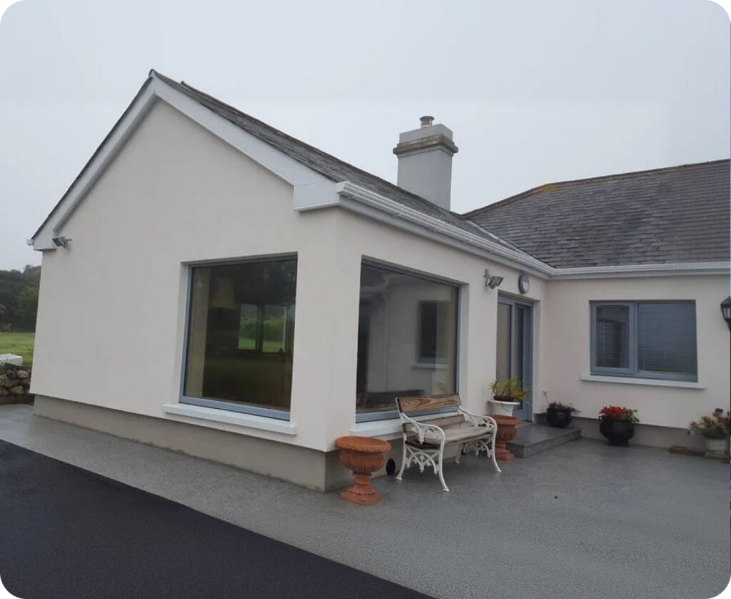 Single-storey rendered home with large windows and a paved patio