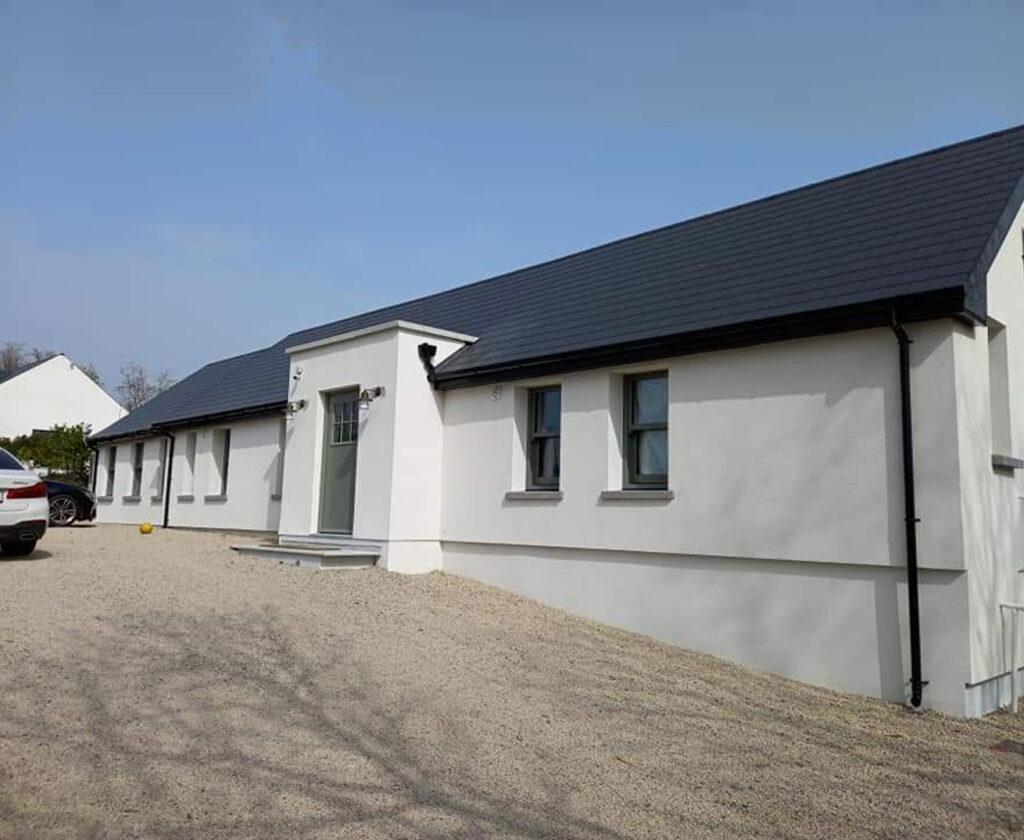 White rendered bungalow with a dark tiled roof and paved driveway